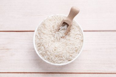 Çiğ basmati pilavı ve kepçeyle beyaz ahşap masa, üst manzara.