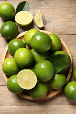 Taze limon ve yeşil yapraklar ahşap masada, düz yatıyordu.
