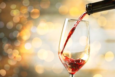 Arka plana kırmızı şarap dökmek bulanık ışıklarla, yakın plan. Metin için boşluk