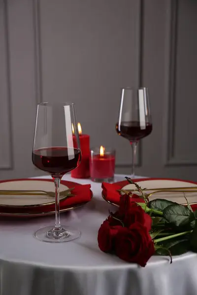 Place setting with roses and candles on white table. Romantic dinner
