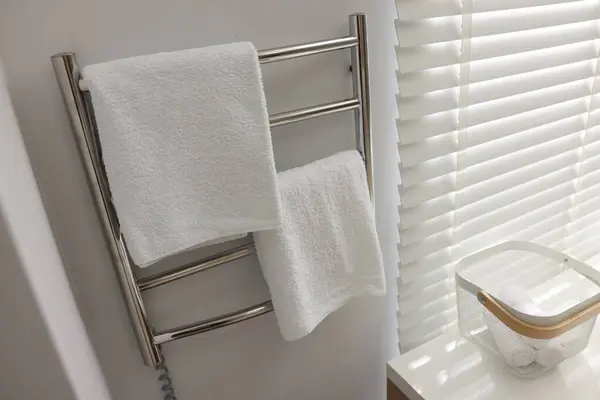 Heated rail with towels on white wall in bathroom