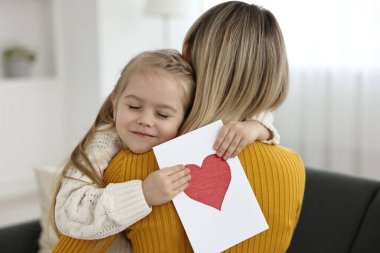 Küçük kızı evde annesini tebrik kartıyla tebrik ediyor. Anneler Günün kutlu olsun.