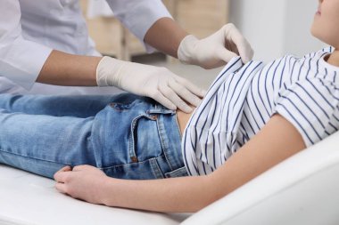 Gastroenterolog klinikte karnı ağrıyan bir kızı muayene ediyor.