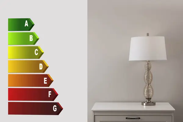Energy efficiency rating label and lamp on bedside table near grey wall indoors