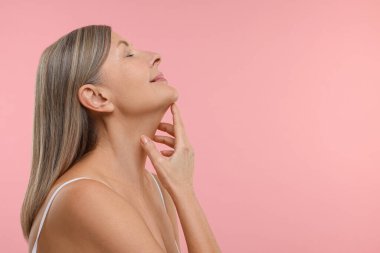Pembe arka planda sağlıklı cildi olan güzel bir kadın, mesaj için yer var.