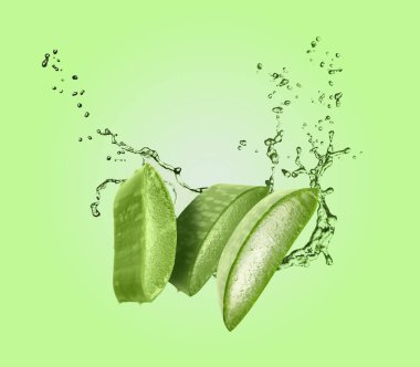 Dilimlenmiş aloe vera yaprağı ve yeşil arka planda biraz meyve suyu.