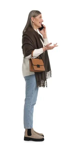 在白色背景下 拿着手提包在智能手机上聊天的老年妇女 — 图库照片