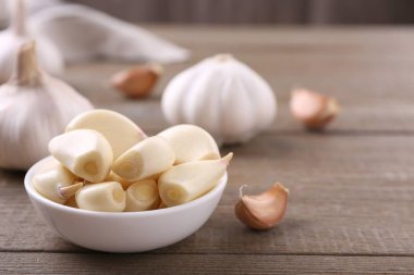 Aromatic garlic cloves and bulbs on wooden table, closeup. Space for text clipart