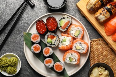 Koyu gri masada lezzetli suşi ruloları olan düz kompozisyon.