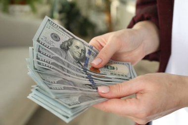 Para değişimi. Bulanık arka planda dolar banknotları sayan kadın, yakın plan