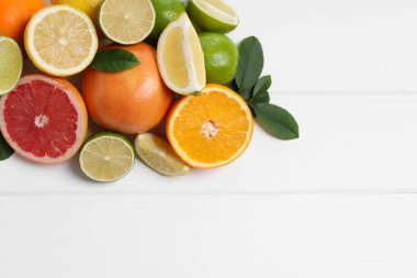 Farklı taze narenciye meyveleri ve beyaz ahşap masa üzerinde yapraklar, düz yatıyordu. Metin için boşluk