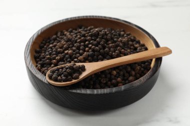 Aromatik baharat. Siyah biber kasede ve kaşık beyaz masada.