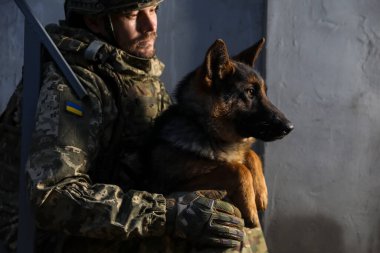 Alman çoban köpeği olan Ukraynalı asker dışarıda duvarın yanında.
