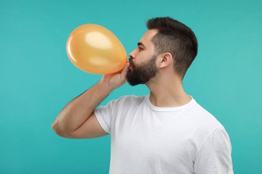 Turkuaz arka planda parlak balon şişiren adam