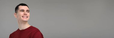 Temiz dişleri olan bir adam gri arka planda gülümsüyor, mesaj için yer var. Pankart tasarımı