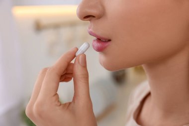 Evde vitamin hapı alan genç bir kadın, yakın plan.