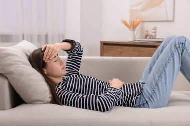 Üzgün kadın kanepenin içinde baş ağrısı çekiyor.