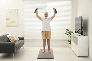 Son sınıf öğrencisi evde spor yaparken lastik bant takıyor.