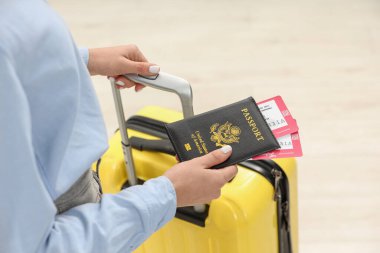 Bavullu kadın, pasaport ve arka planı bulanık biletler, yakın plan.