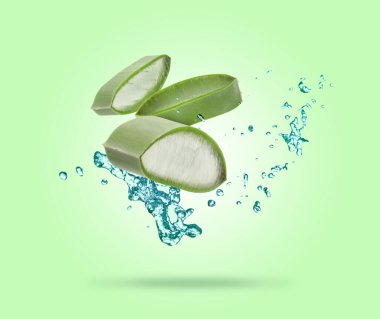 Dilimlenmiş aloe vera yaprağı ve yeşil arka planda biraz meyve suyu.