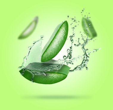 Dilimlenmiş aloe vera yaprağı ve yeşil arka planda biraz meyve suyu.