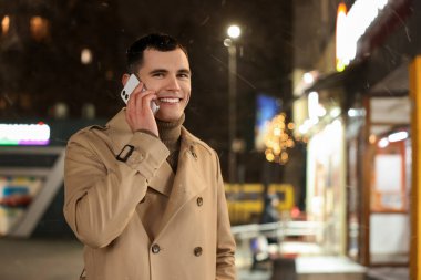 Gece caddesinde akıllı telefondan konuşan adam, mesaj için yer.