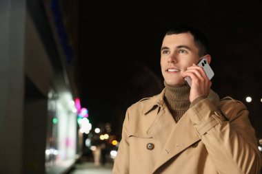 Gece caddesinde akıllı telefondan konuşan adam, mesaj için yer.