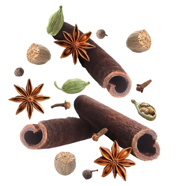 Tarçın çubukları ve beyaz arkaplana dökülen diğer aromatik baharatlar