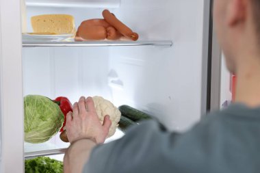Buzdolabından karnabaharı çıkaran adam, yakın plan.