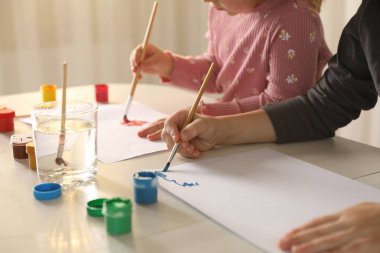 Küçük çocuklar ahşap masada fırçayla resim çiziyorlar, yakın plan.