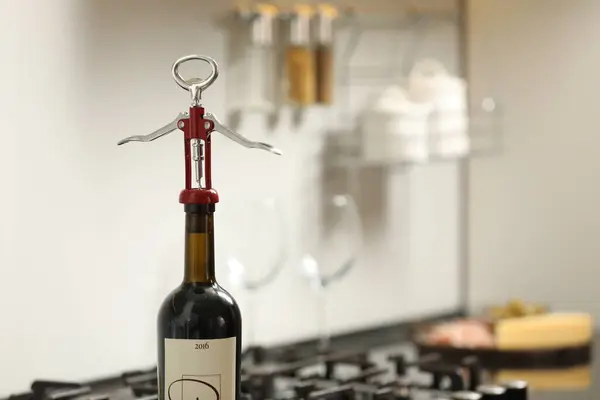 Wine bottle with metal corkscrew in kitchen. Space for text