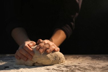 Ekmek yapıyorum. Masada hamur yoğuran bir kadın, yakın plan. Metin için boşluk