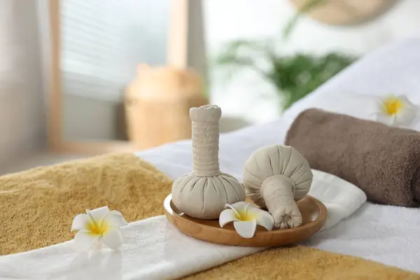 Herbal bags, flowers and towels on massage table in spa