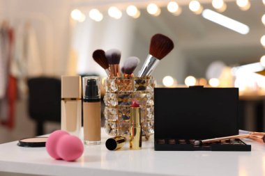 Makyaj odasındaki beyaz masada farklı kozmetik ürünleri.