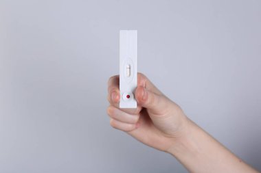 Açık gri arkaplan üzerinde tek kullanımlık ekspres test tutan kadın, yakın plan