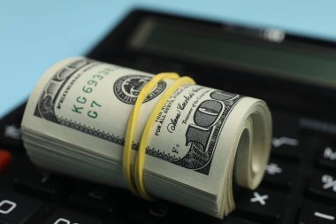 Para değişimi. Açık mavi arkaplanda dolar banknotları ve hesap makinesi, yakın plan