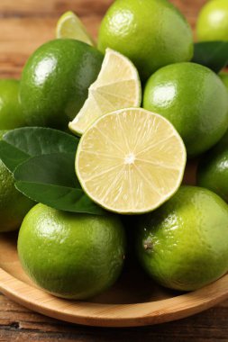 Taze limon ve yeşil yapraklar ahşap masada, yakın plan.