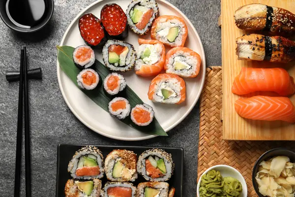 Flat lay composition with delicious sushi rolls on dark grey table