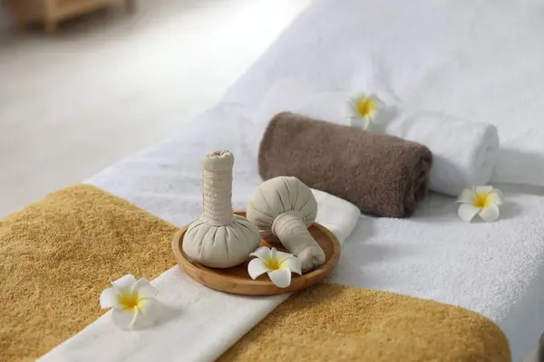 Herbal bags, flowers and towels on massage table in spa