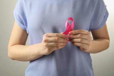 Açık gri arka planda pembe kurdeleli kadın, yakın plan. Göğüs kanseri farkındalığı