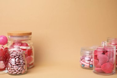 Bej arka planda cam kavanozlarda lezzetli pembe şekerler, metin için yer