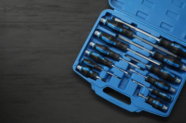 Siyah ahşap masadaki açık alet çantasındaki tornavidalar, üst manzara. Metin için boşluk