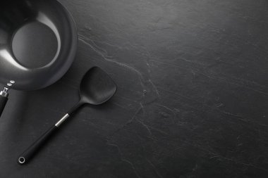 Siyah metal wok ve spatula koyu dokulu masa, üst görünüm. Metin için boşluk