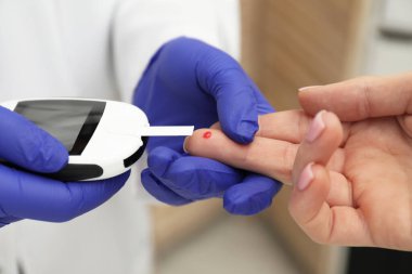 Diyabet. Doktor kan şekerini klinikte glukometreyle ölçüyor.