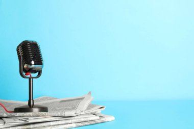 Gazeteler ve açık mavi arka planda klasik mikrofon, mesaj için yer. Gazeteci işi.