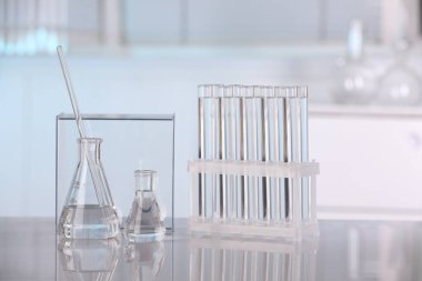 Laboratuvar analizi. Cam mataralar, test tüpleri ve beyaz masada karıştırıcı çubuklar.