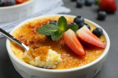 Lezzetli creme brulee kasede böğürtlen ve gri masada kaşık, yakın plan