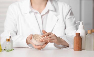 Beyaz masa içinde kavanoz testi kozmetik ürünü olan dermatolog, seçici odaklanma