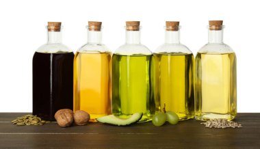 Sebze yağları. Beyaz arka planda, ahşap masanın üzerinde farklı yemek yağları ve malzemeler var.