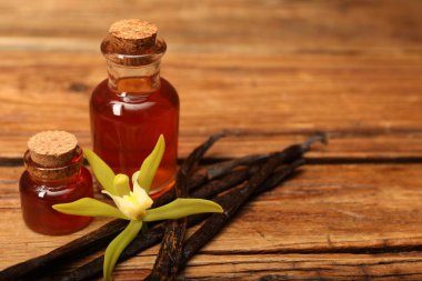 Aromatik vanilya özü, kapsüller ve çiçek ahşap masada, yakın plan. Metin için boşluk